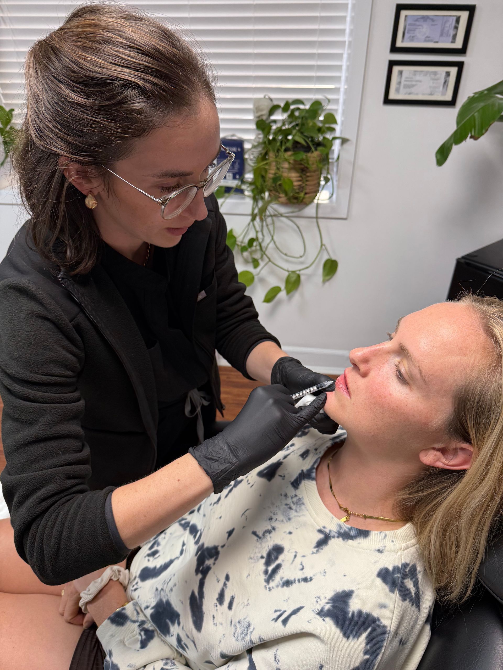 A person receives a lip injection from a medical professional. They are in a clinic setting.