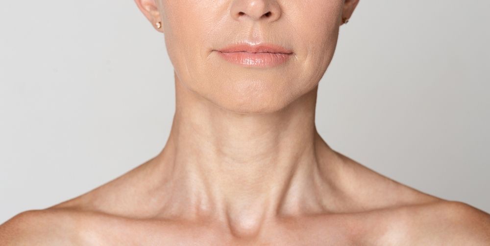 Close-up of a bare neck and shoulders against a plain light background
