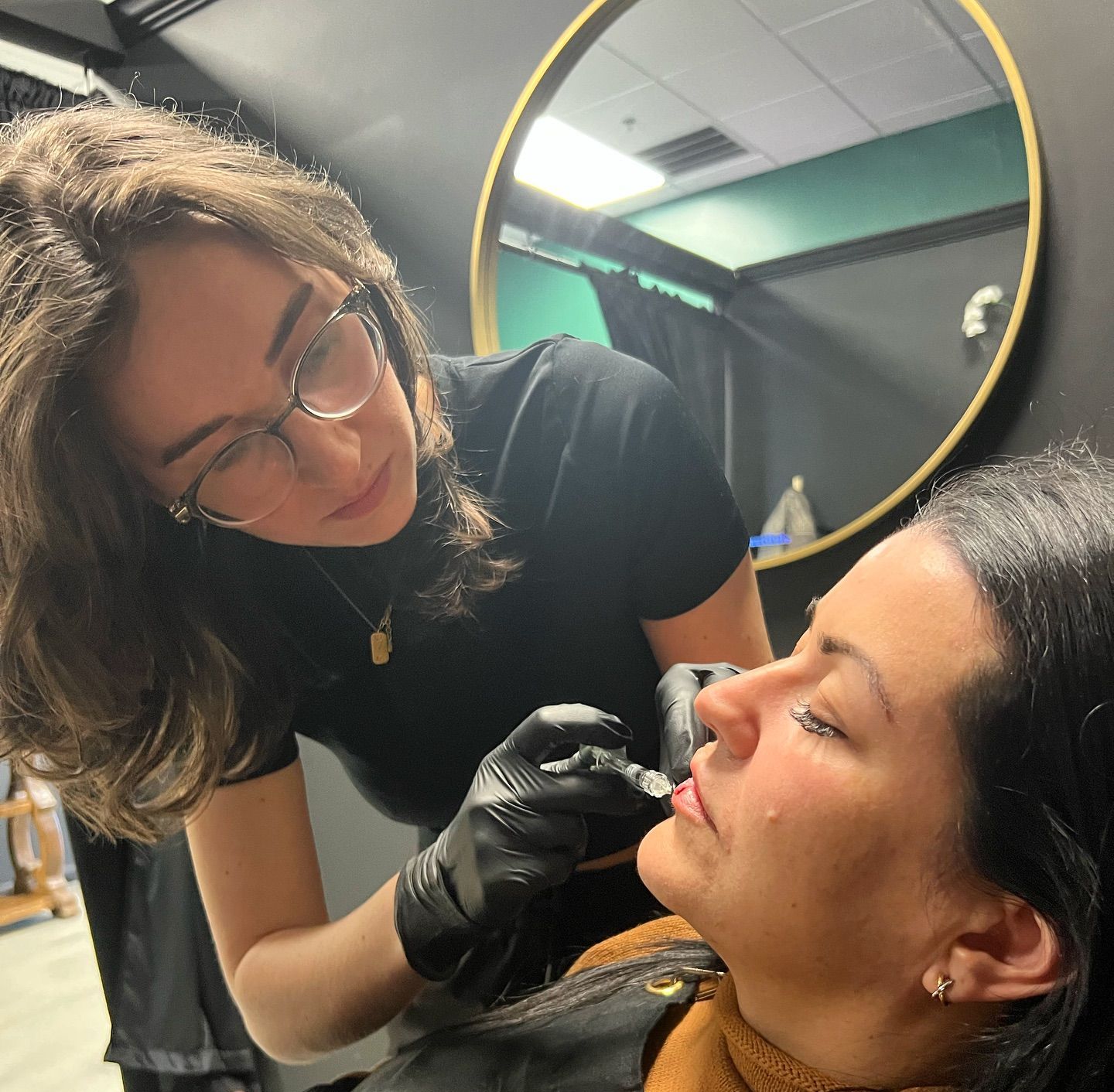 A woman is applying makeup to another woman 's face in front of a mirror.