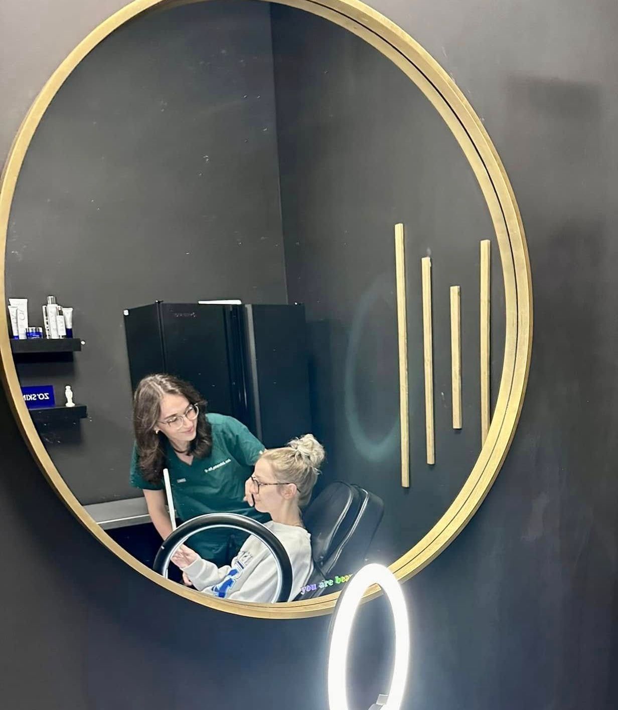 A woman is getting her hair done in front of a mirror