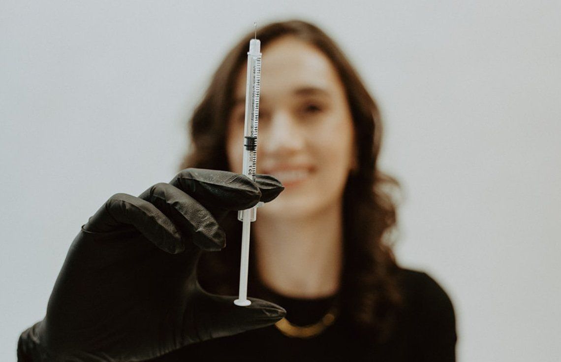 A woman is holding a syringe in her hand.