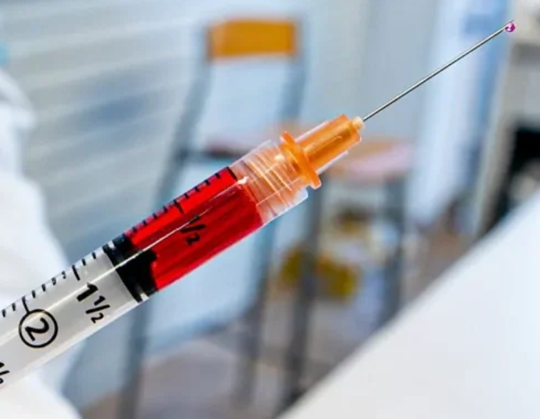 A syringe is filled with red liquid and has a needle sticking out of it.