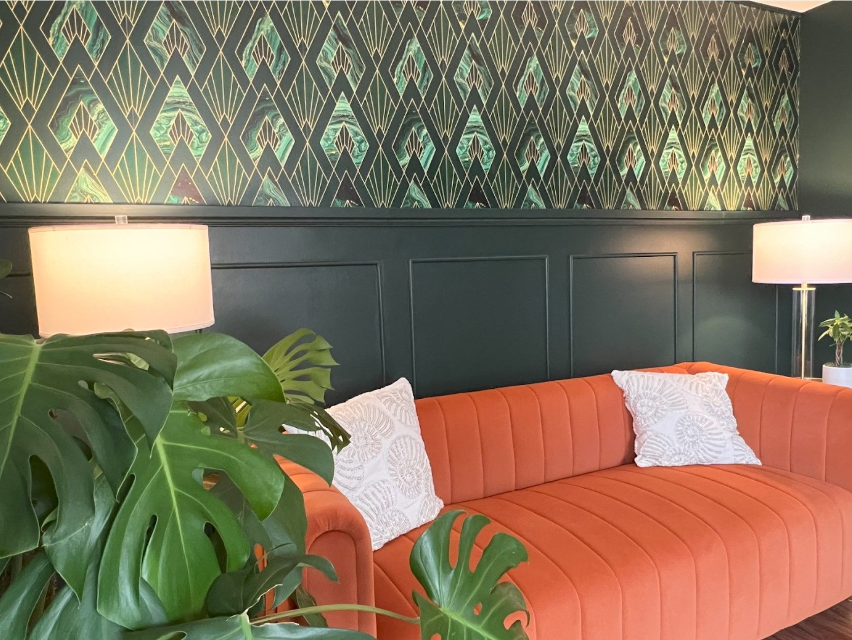 A living room with a couch , lamps , and a plant.