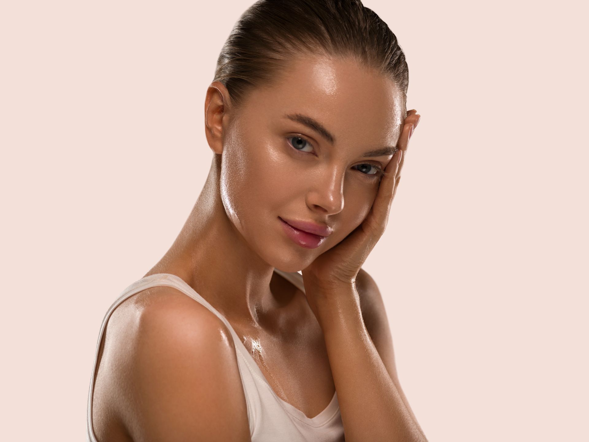 A woman is touching her face with her hand and looking at the camera.