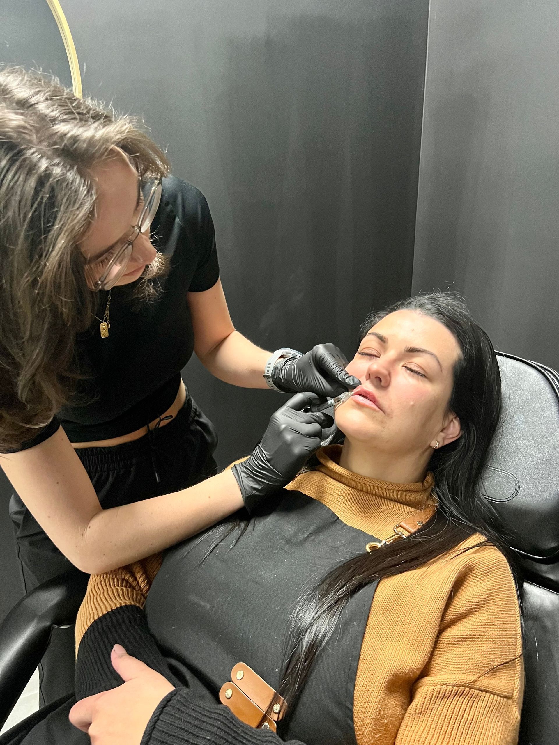 A woman is getting her eyebrows done by a woman in a chair.