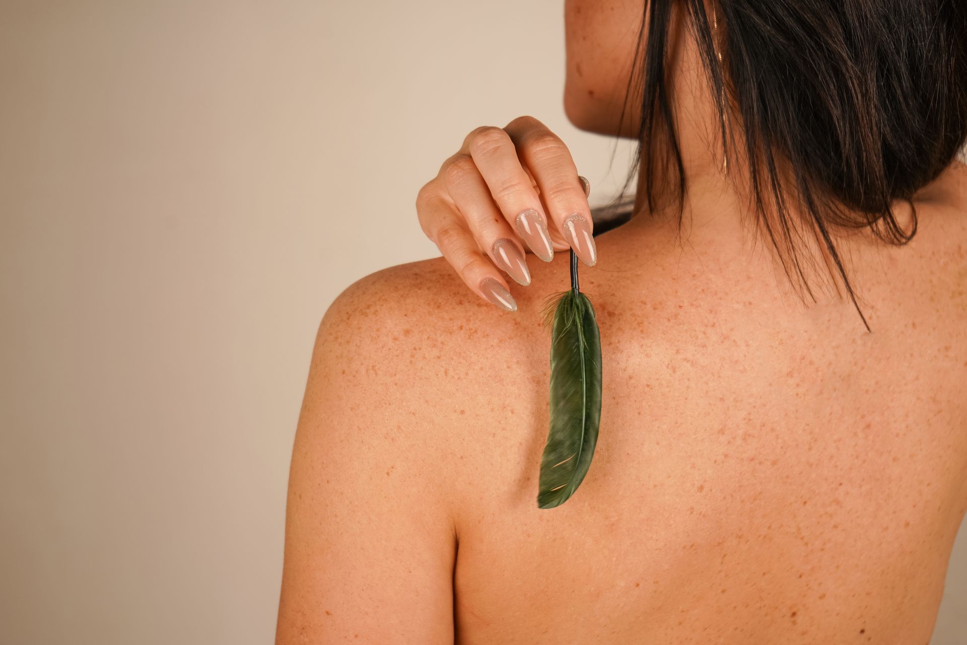 A woman is holding a green leaf on her back.