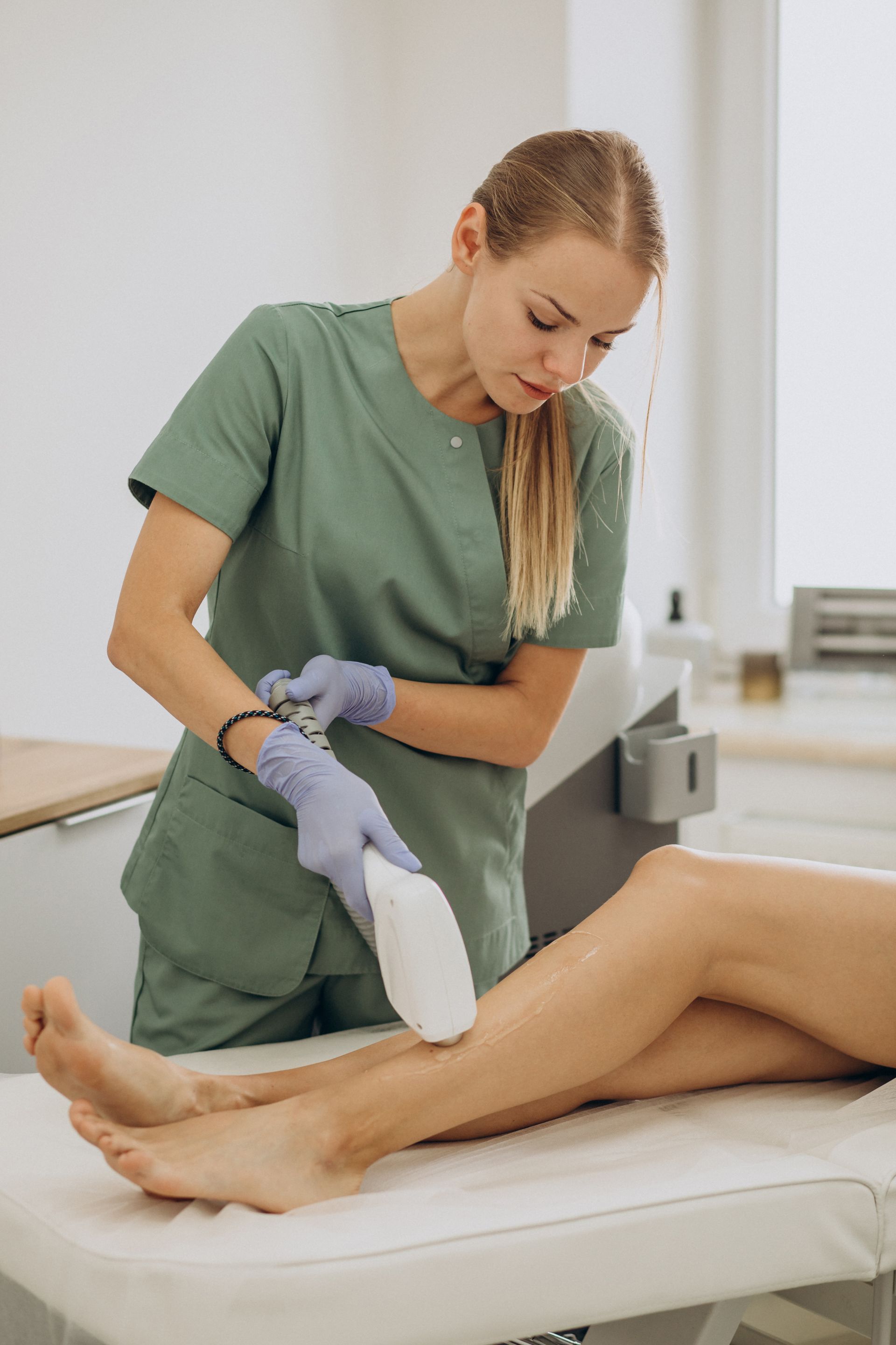 A woman is using a machine to remove hair from a woman 's legs.