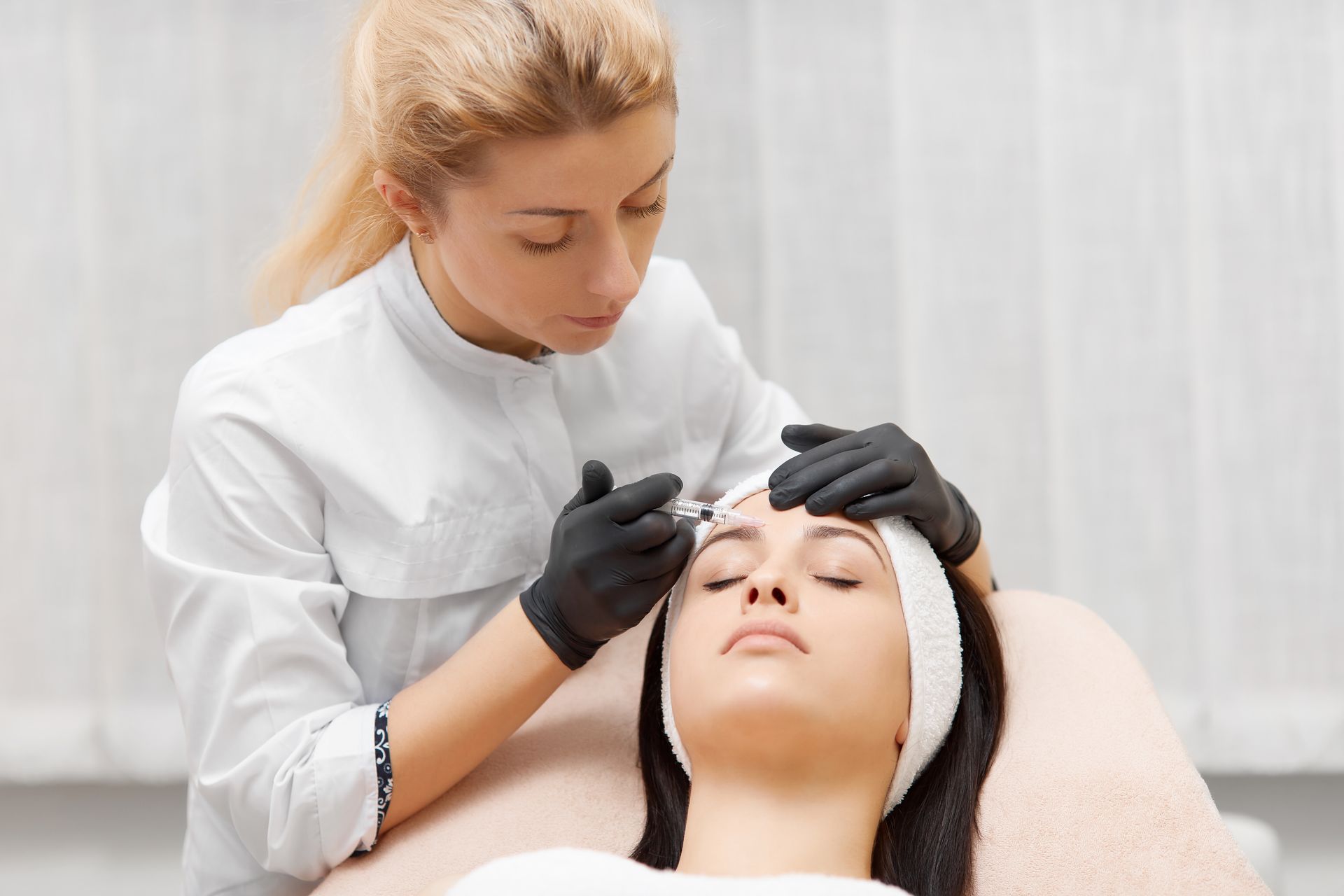 A woman is getting an injection in her eyebrows in a beauty salon.