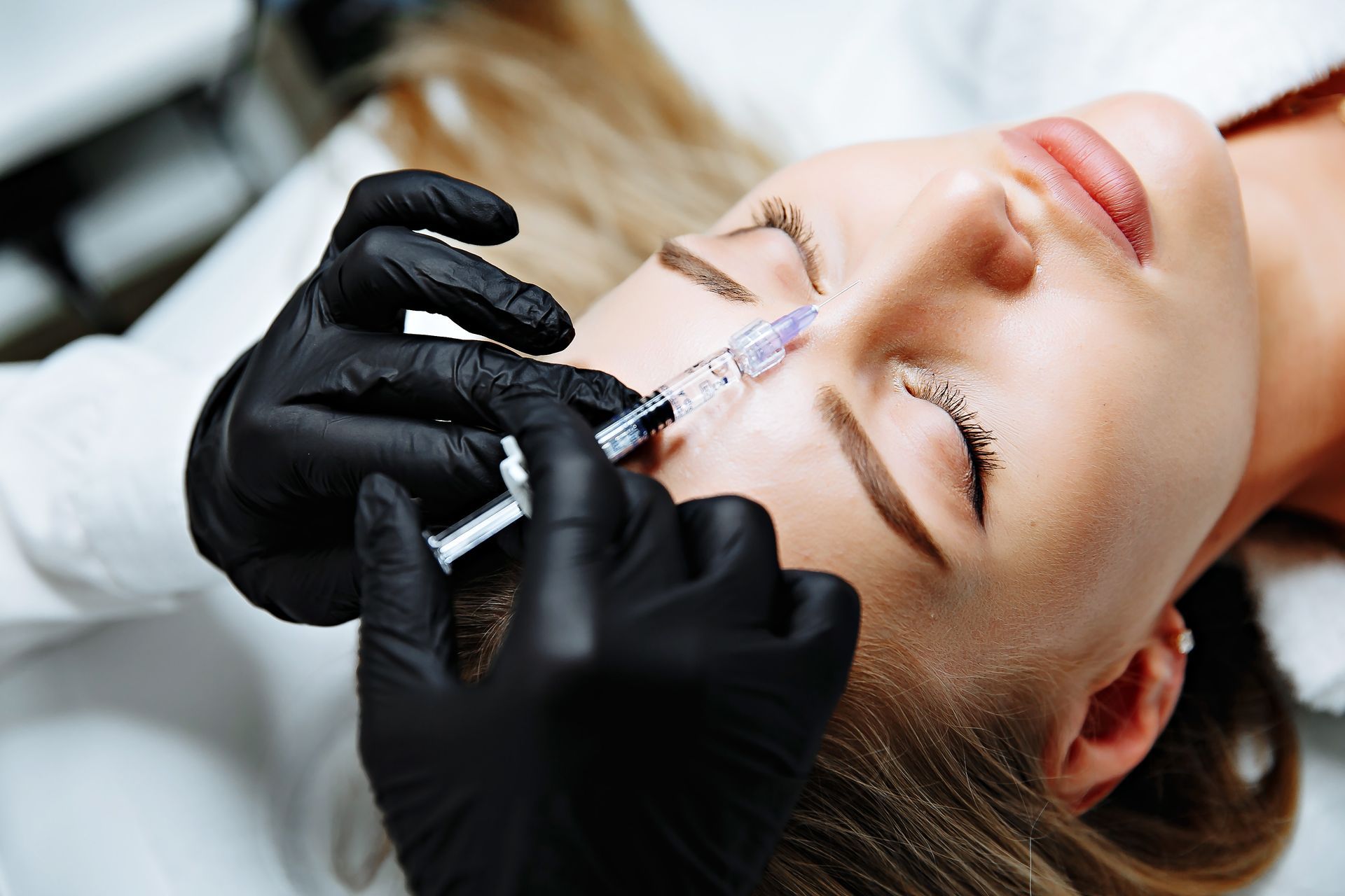 A woman is getting a botox injection in her forehead.