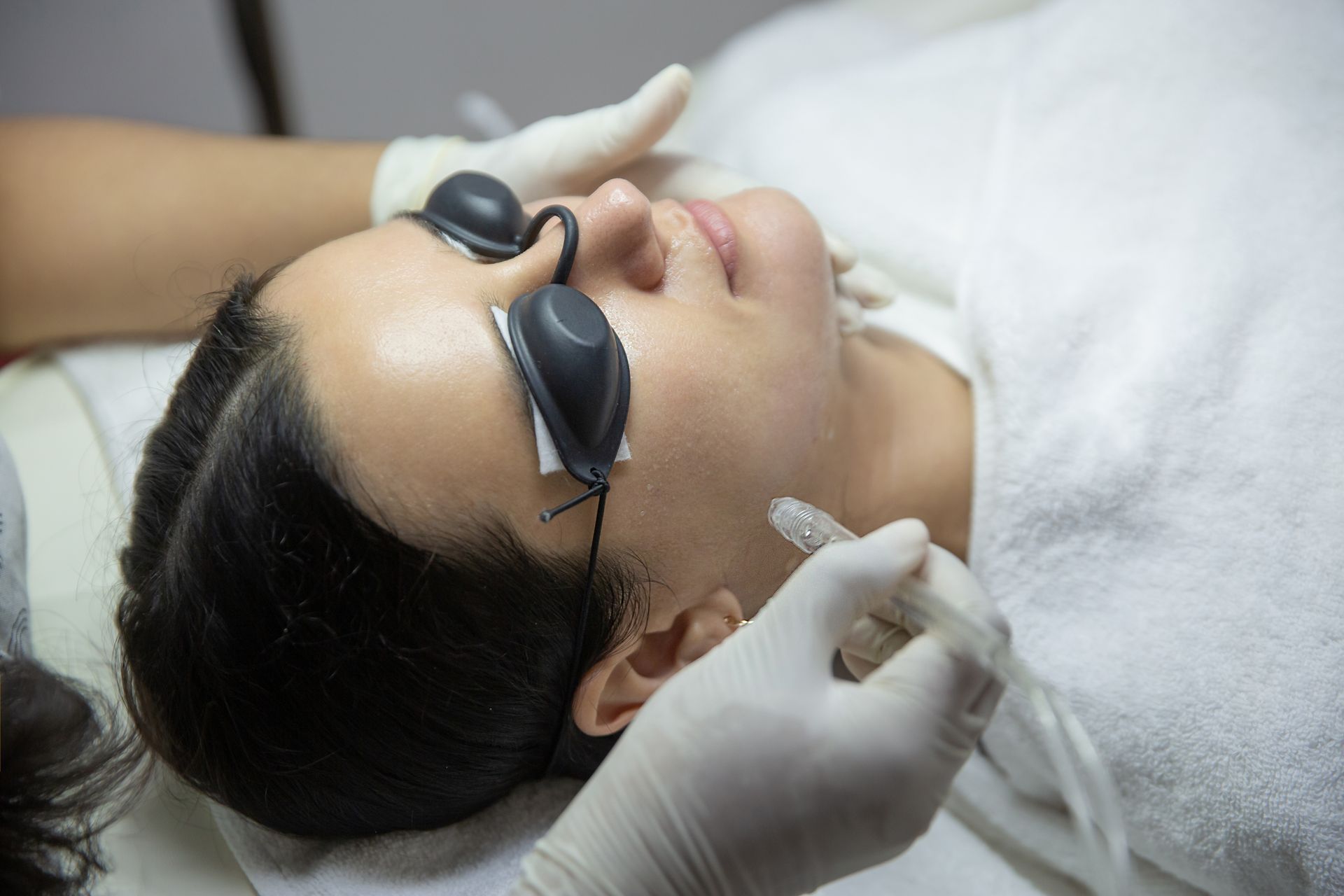 A woman is getting a laser treatment on her face.