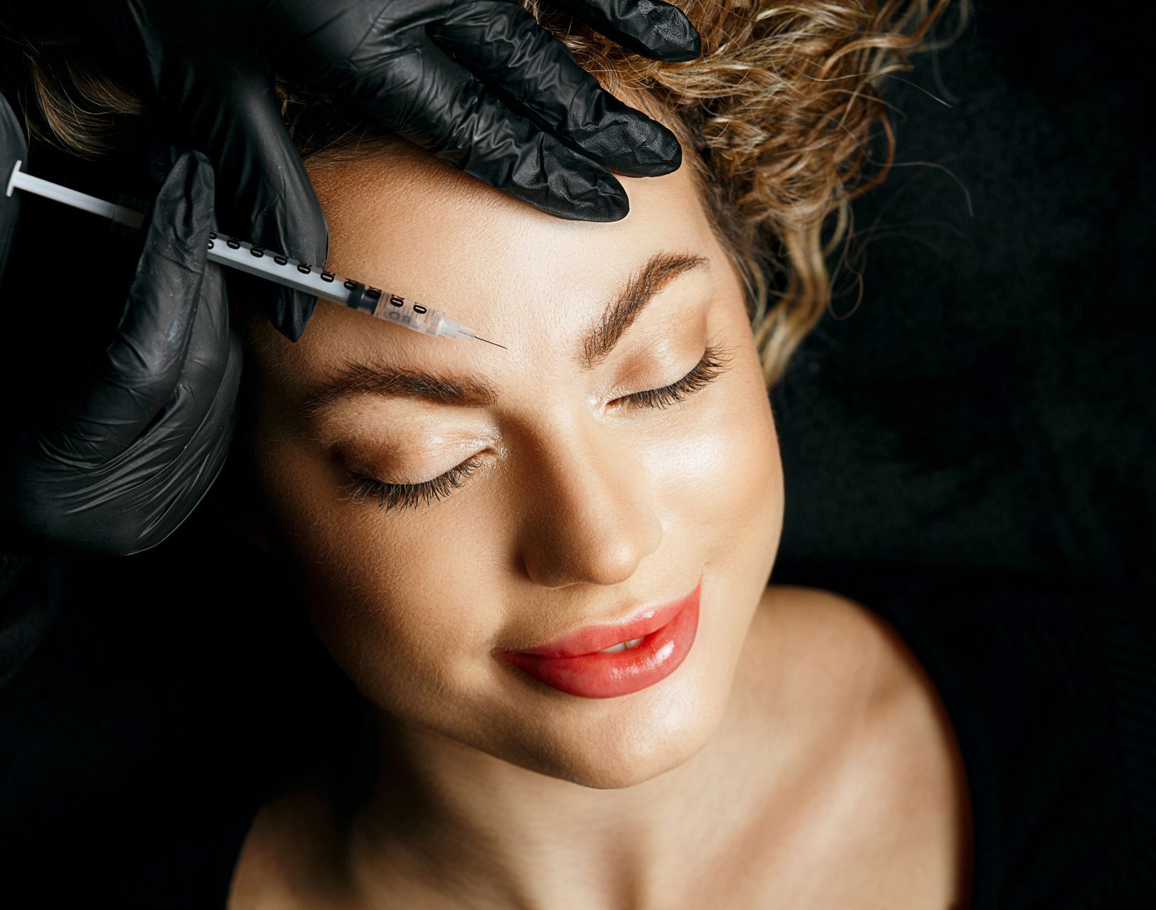 A woman is getting a botox injection in her forehead.