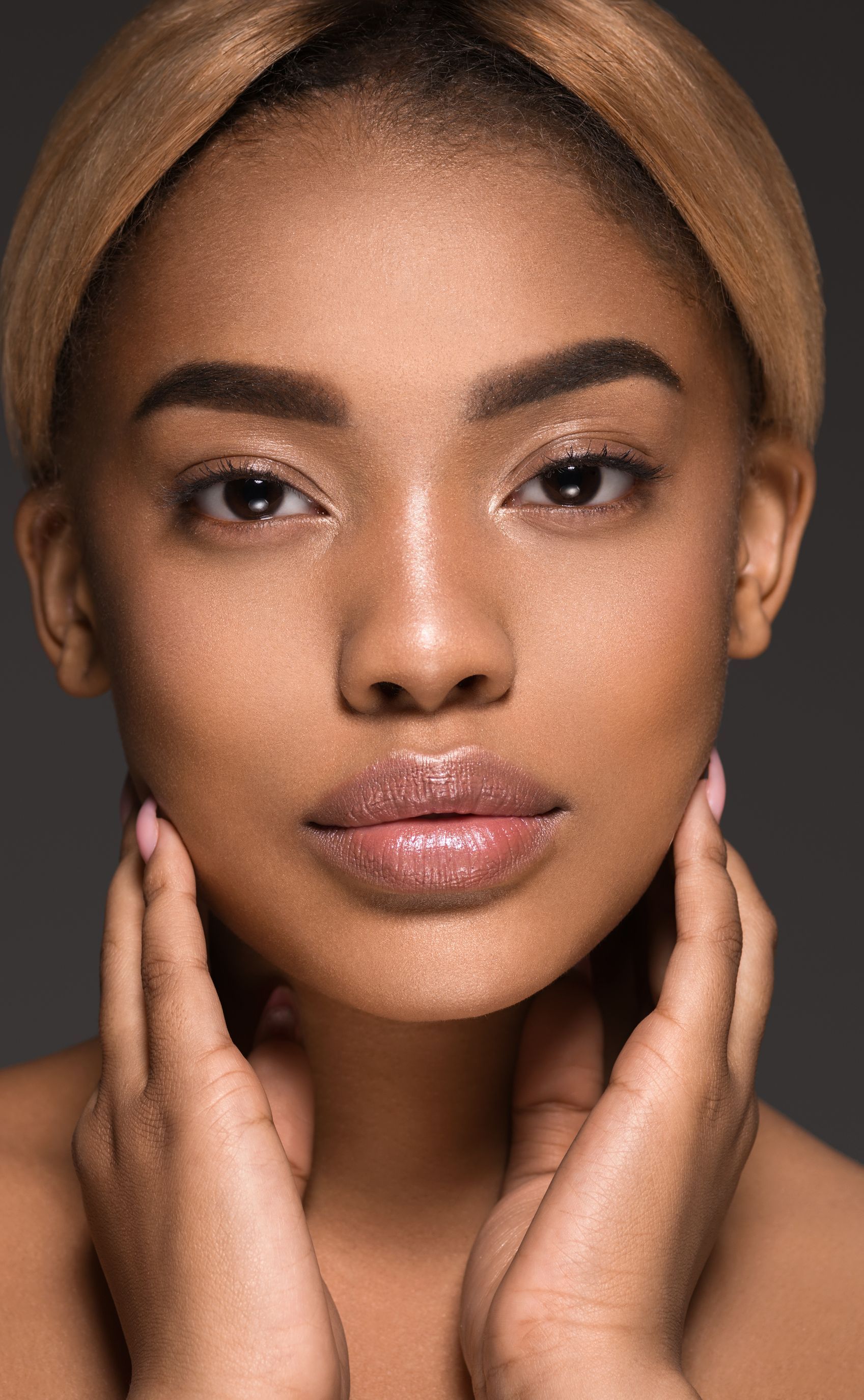 A close up of a woman 's face with her hands on her chin.