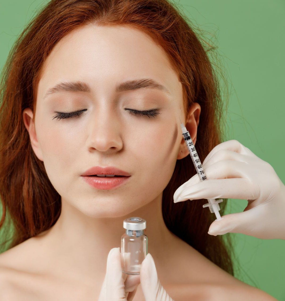 A woman is holding a syringe in front of her face