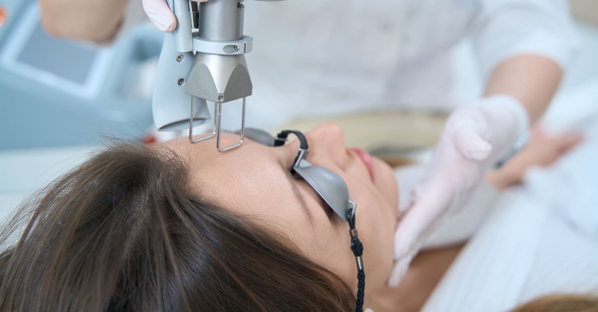 A woman is getting a laser treatment on her face.
