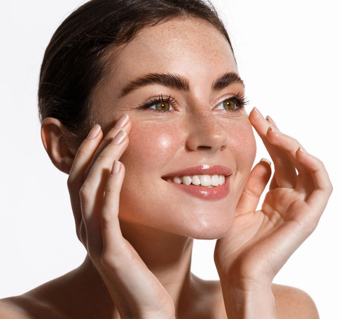 A woman is smiling and touching her face with her hands
