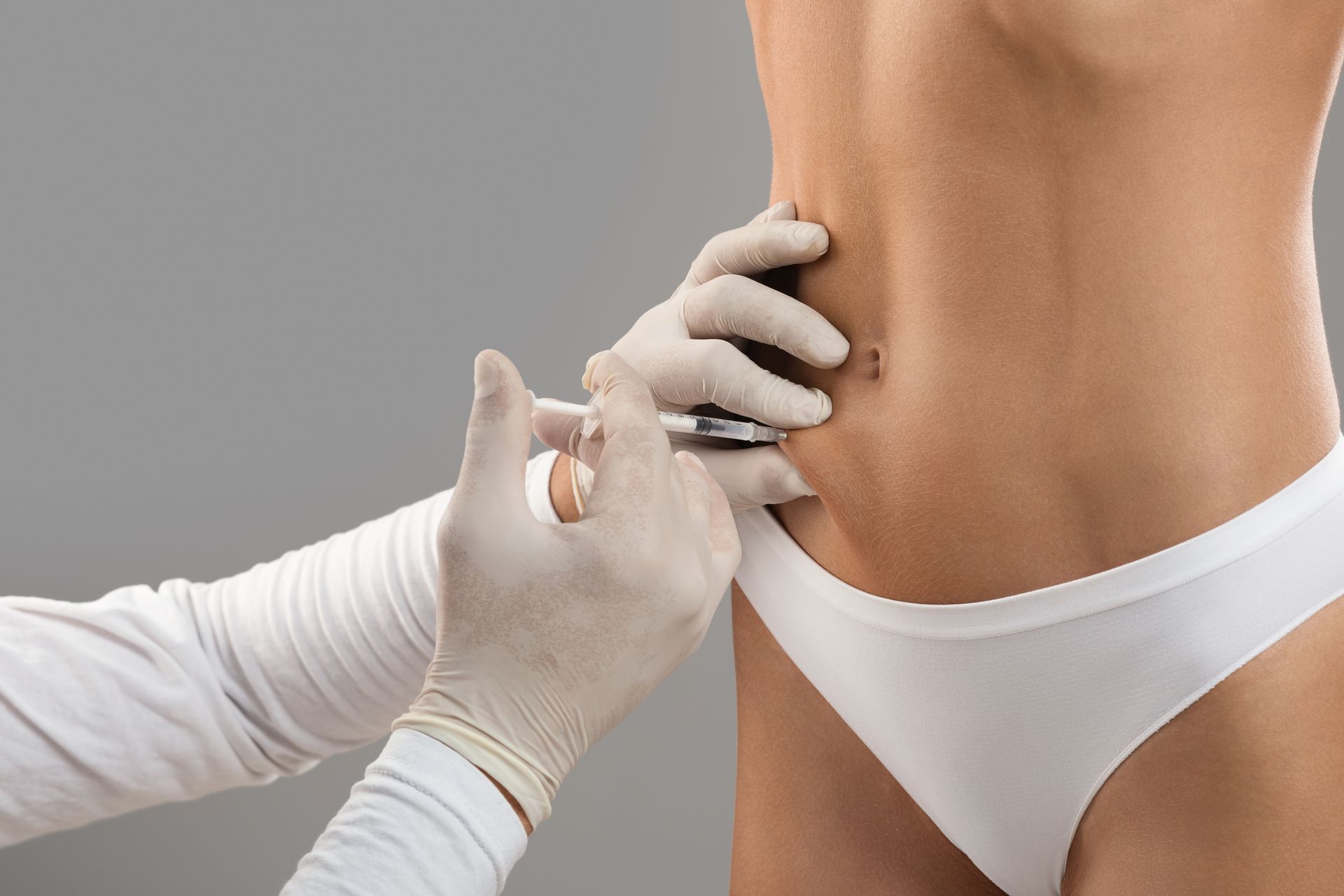 A woman is getting an injection in her stomach.