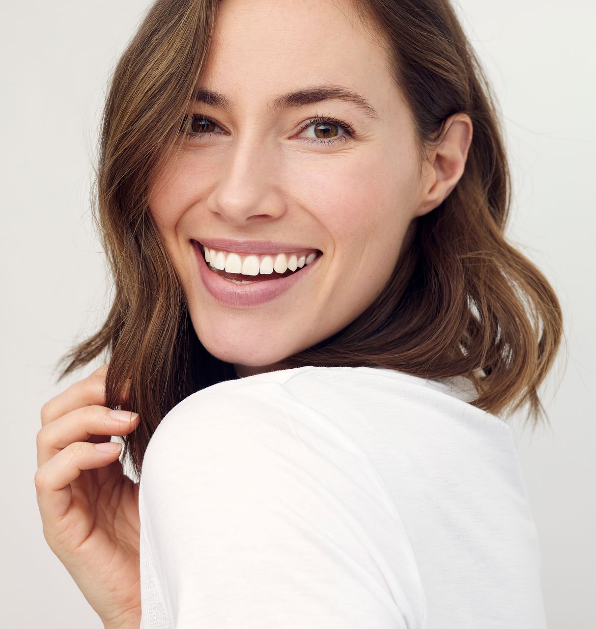 A woman is smiling and looking over her shoulder