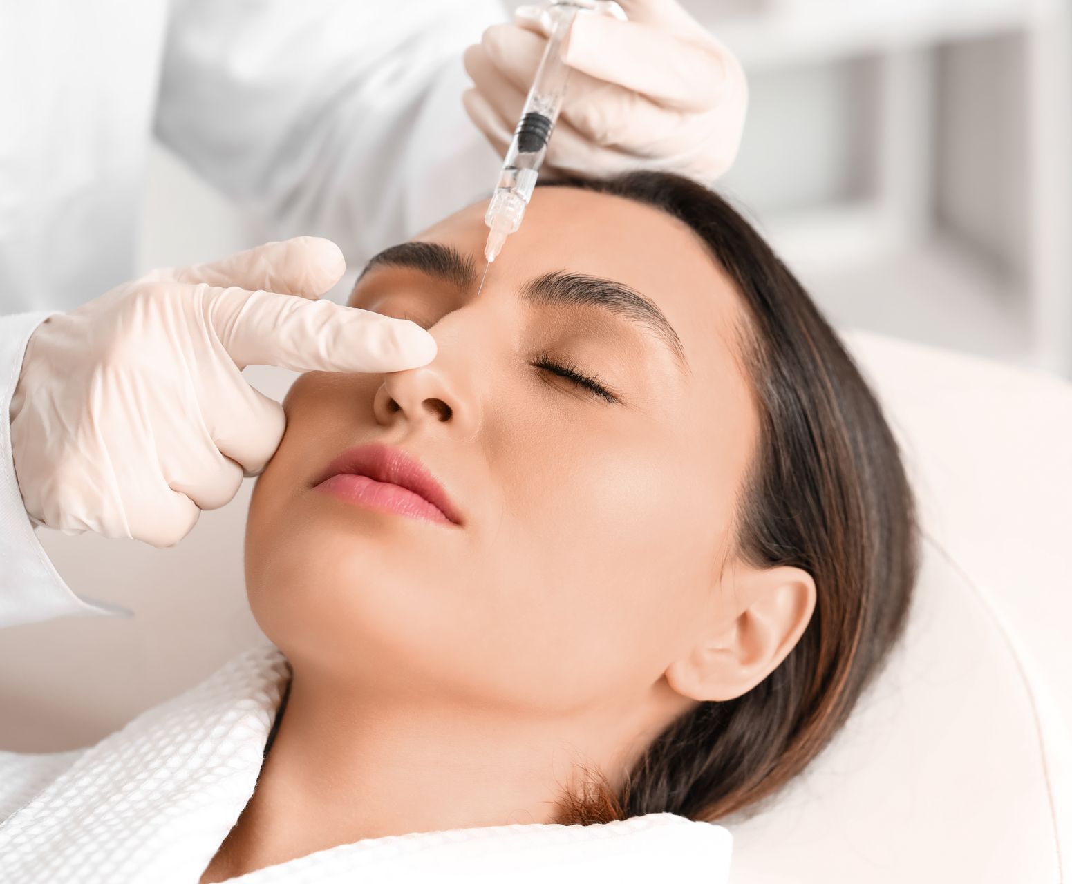 A woman is getting a botox injection in her forehead.