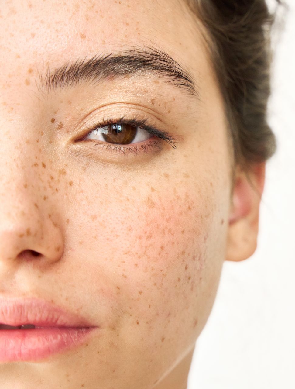 A close up of a woman 's face with freckles and a brown eye.