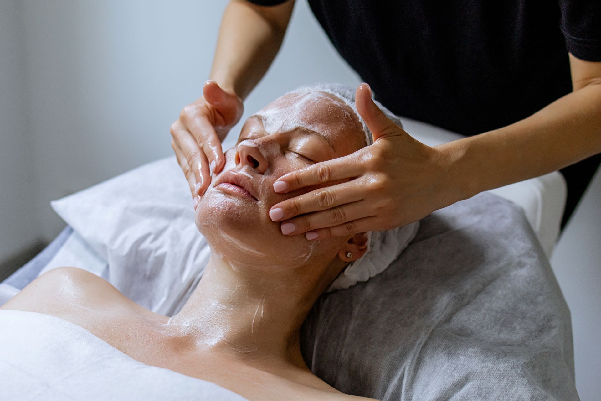 A woman is getting a facial massage at a spa.