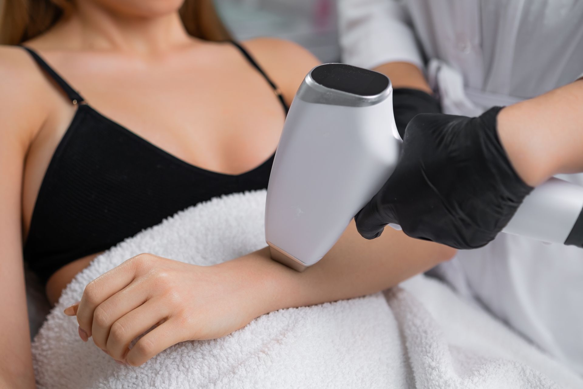 A woman is getting a laser hair removal treatment on her arm.