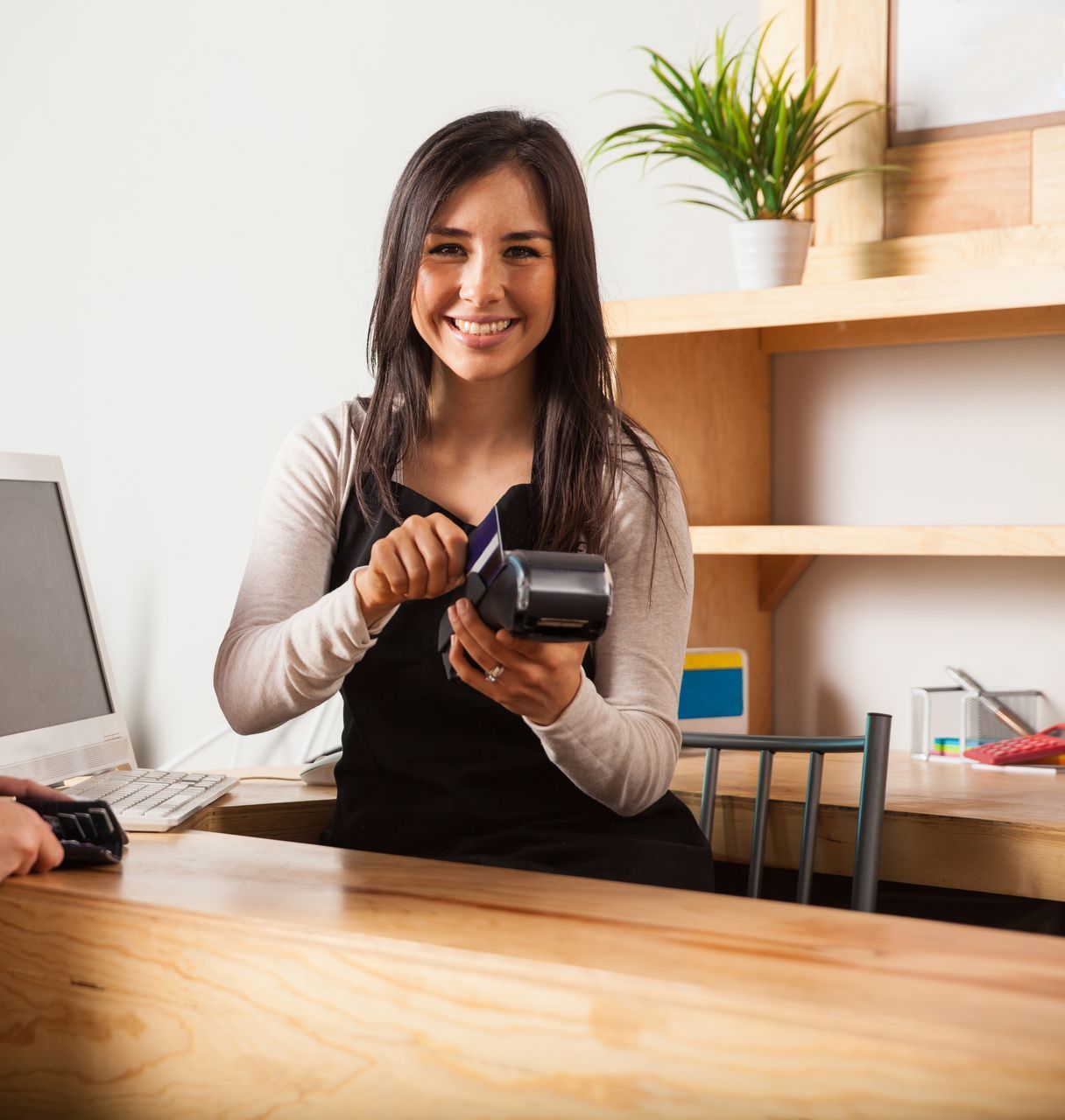 A woman is smiling while holding a credit card reader