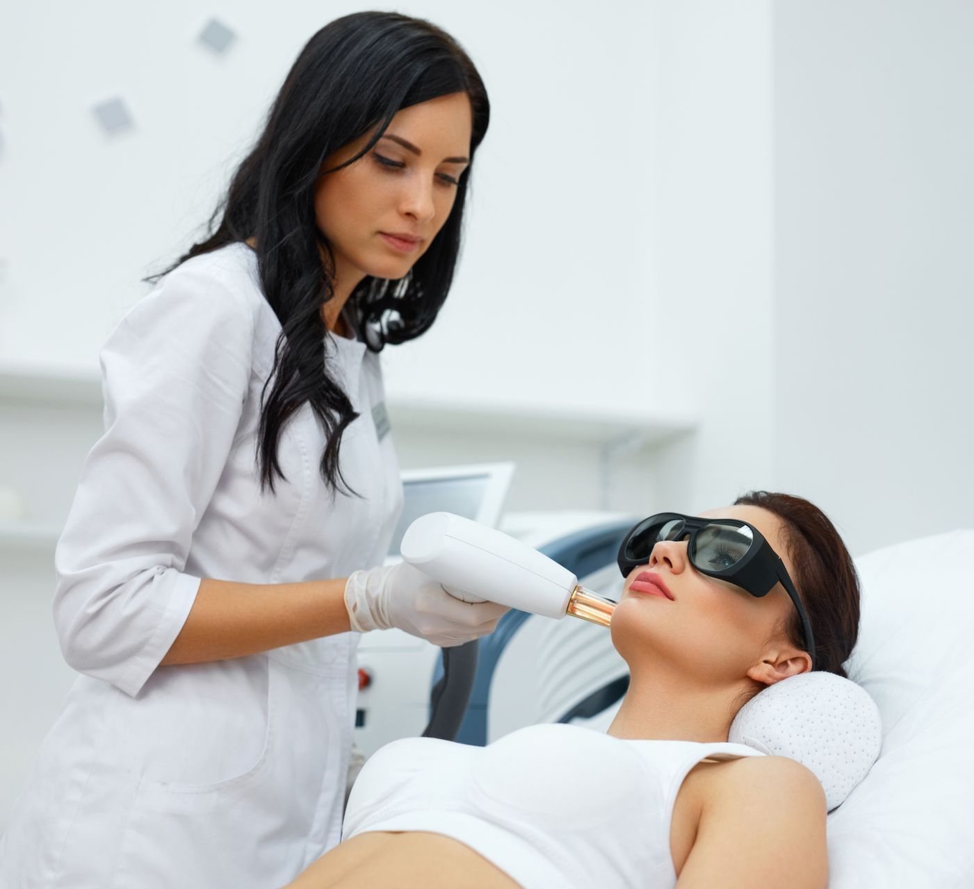 A woman wearing sunglasses is getting a laser treatment on her face