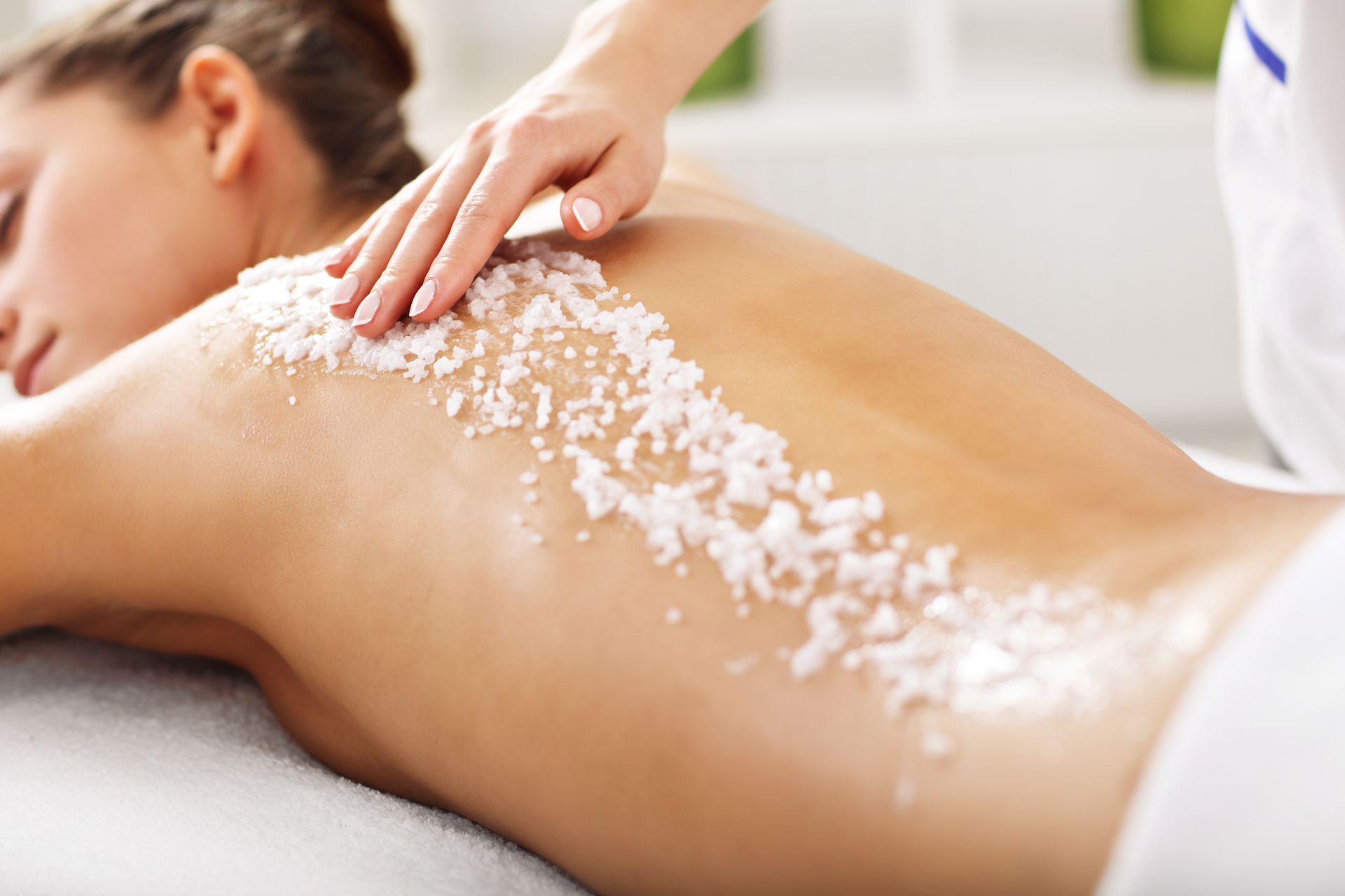 A woman is getting a massage with sea salt on her back.