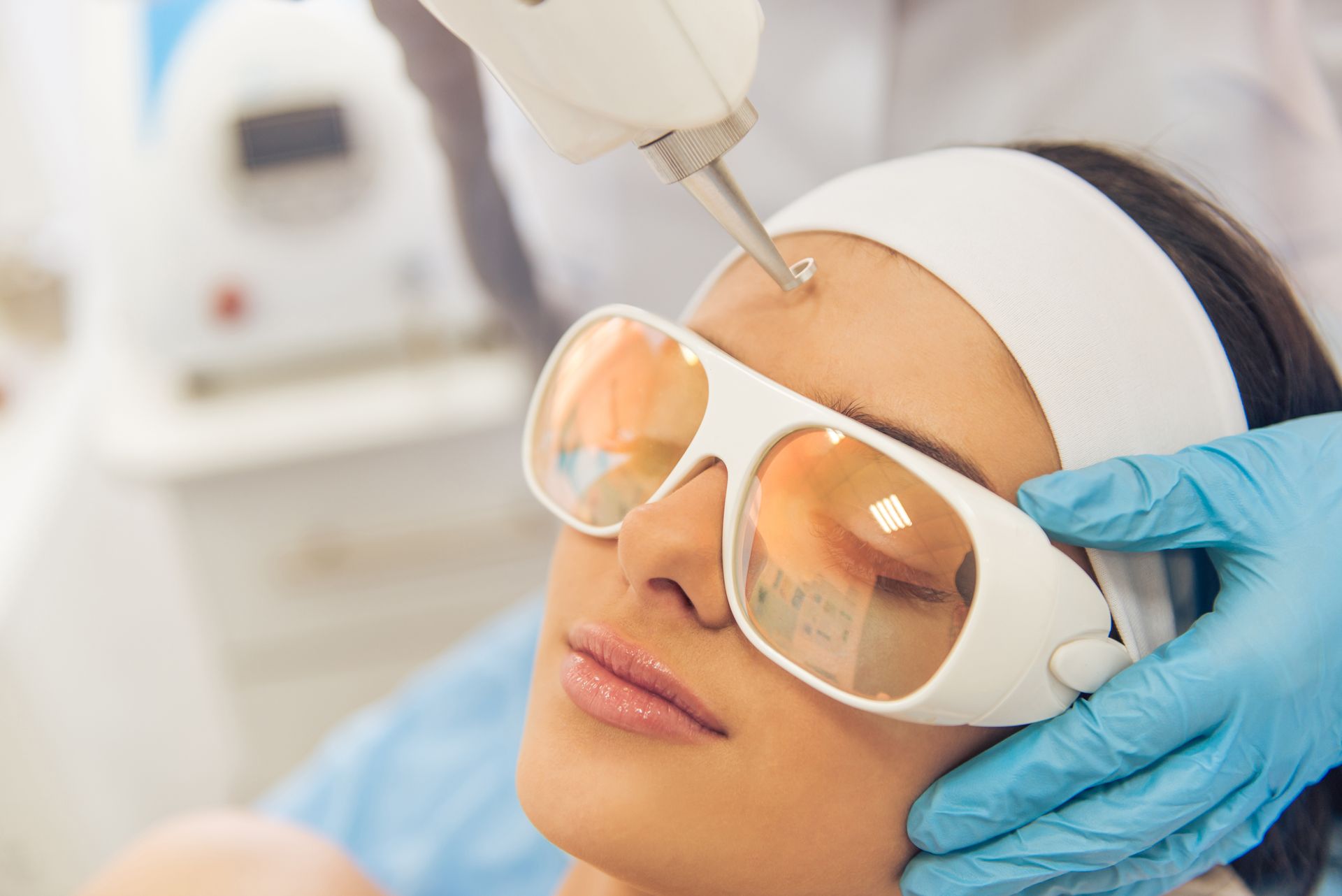 A woman is getting a laser treatment on her forehead.