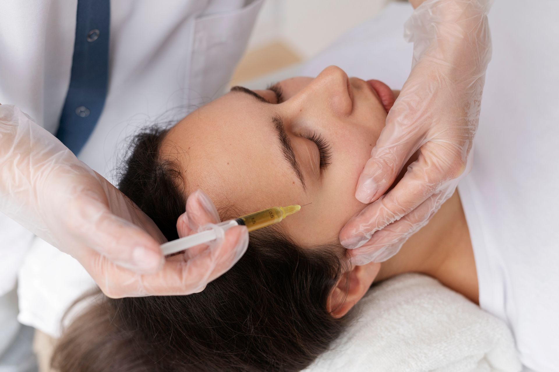 A woman is getting a botox injection in her forehead.