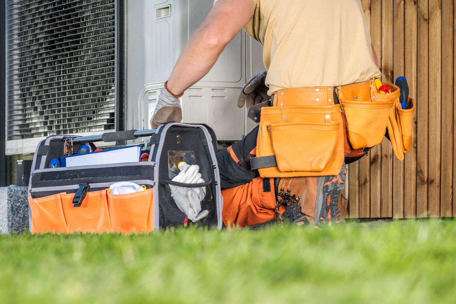 A man is kneeling down next to a tool bag.