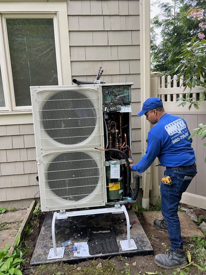A man is working on an air conditioner outside of a house.