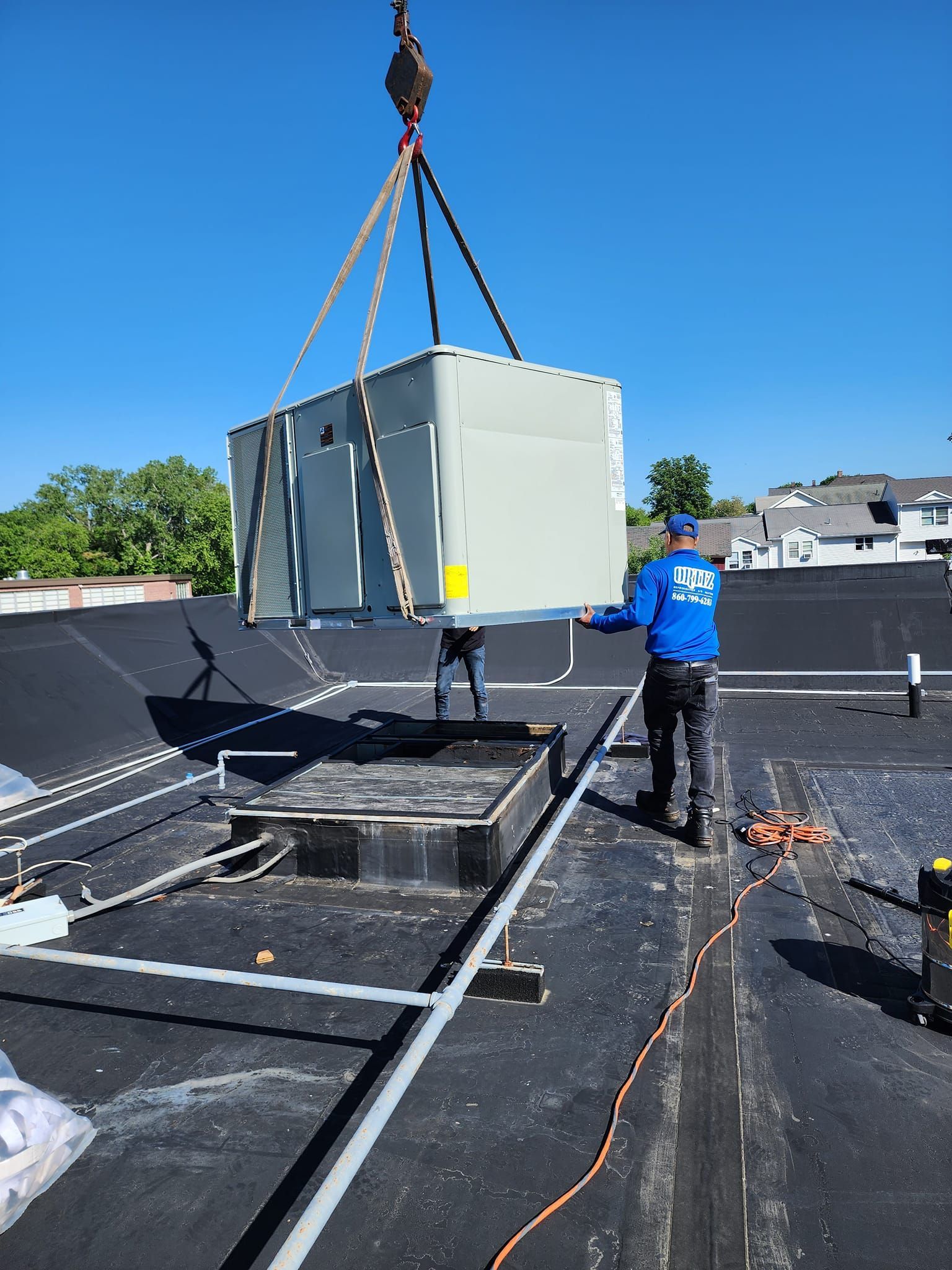A man is lifting a large box on top of a roof with a crane.