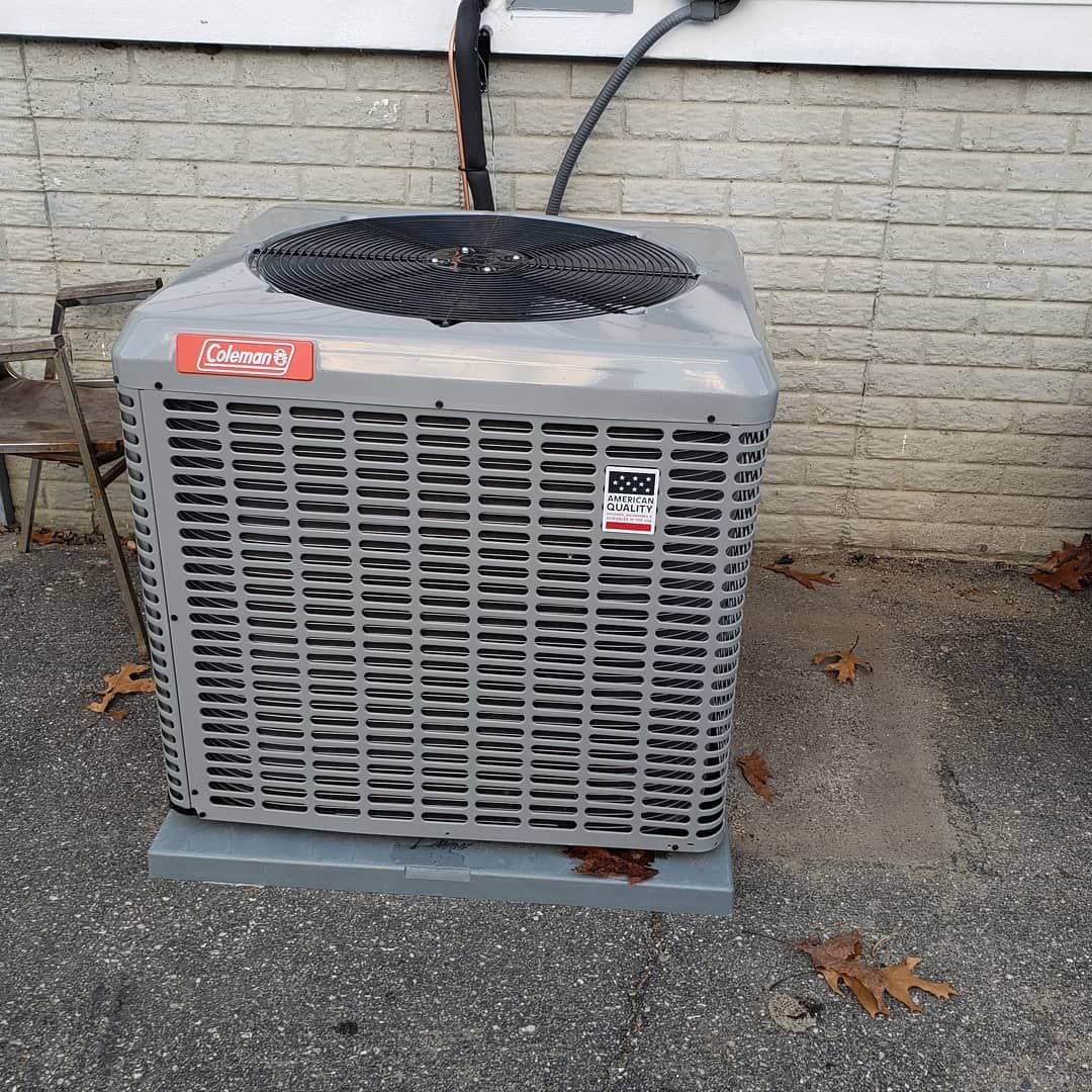 An air conditioner is sitting outside of a brick building.