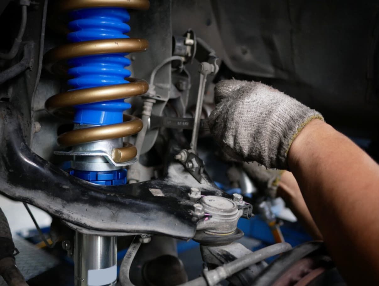 A Person Is Working On A Shock Absorber On A Car — Ultra Mechanics In Warana, QLD