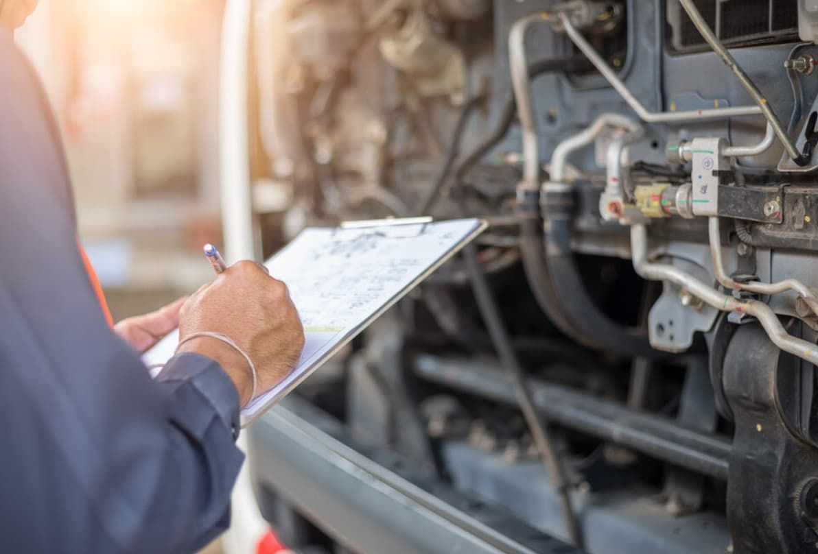 A Man Is Writing On A Clipboard In Front Of A Truck — Ultra Mechanics In Warana, QLD