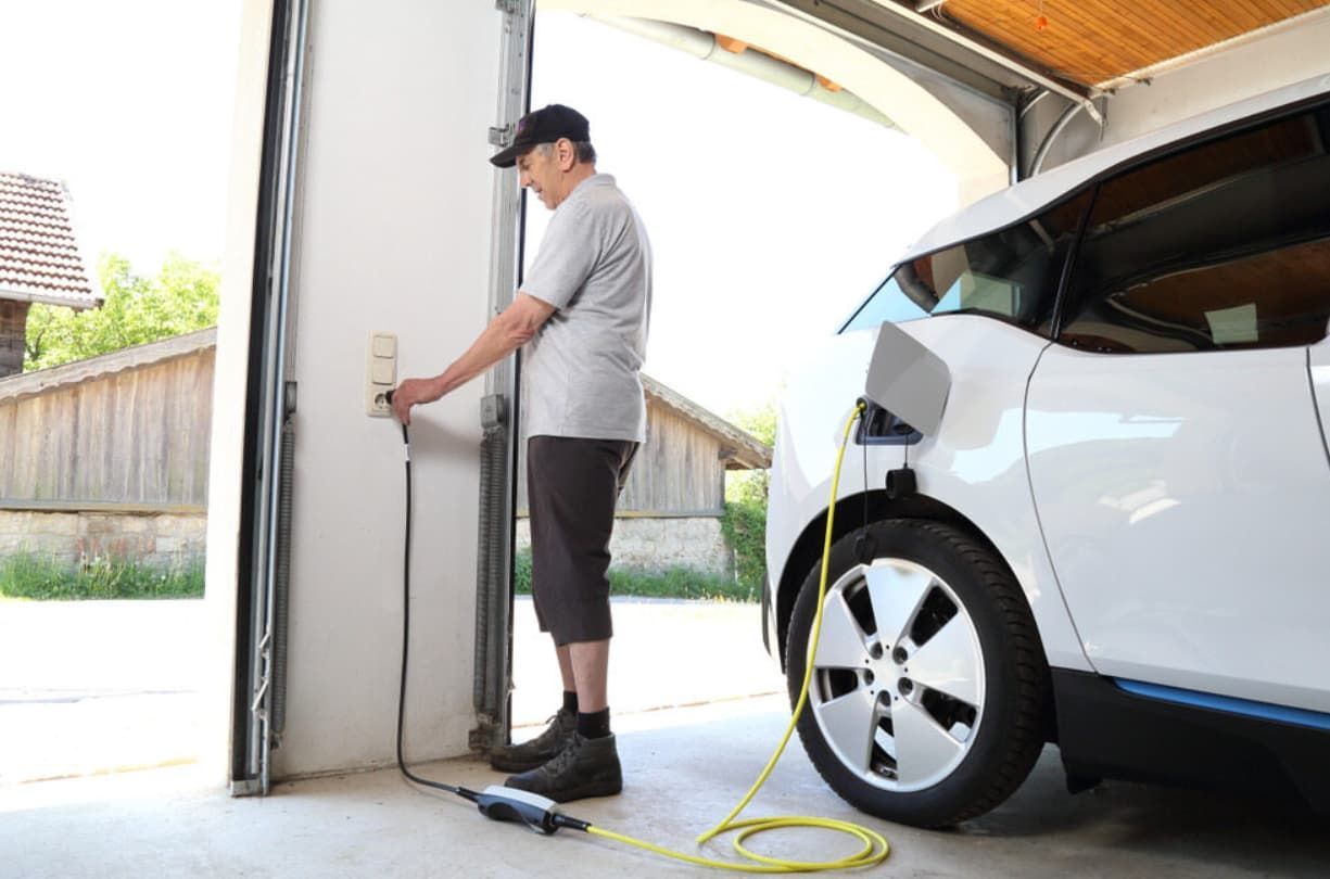 A Man Is Charging An Electric Car In A Garage — Ultra Mechanics In Warana, QLD
