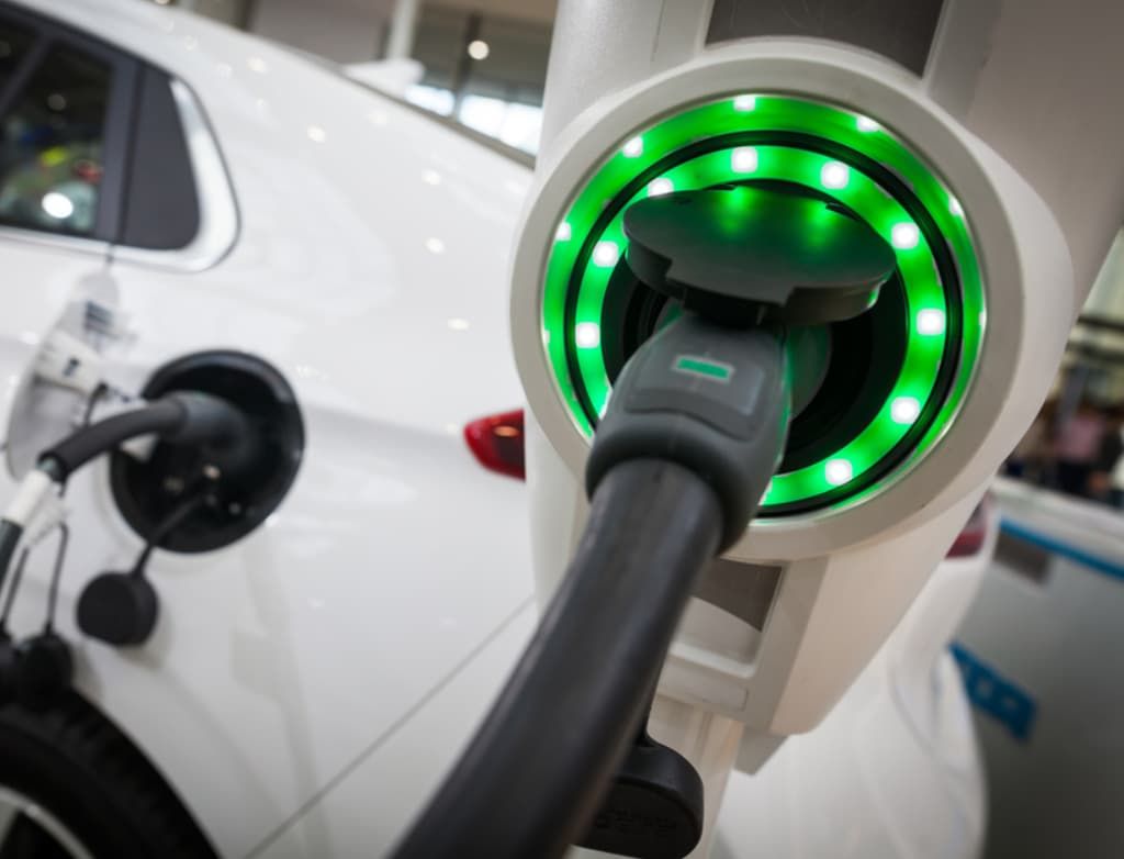 A White Electric Car Is Being Charged At A Charging Station — Ultra Mechanics In Warana, QLD