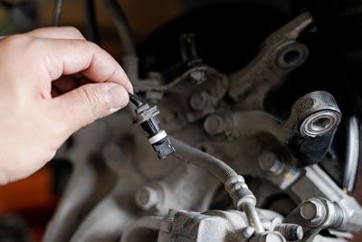 A person is fixing a brake sensor on a motorcycle.