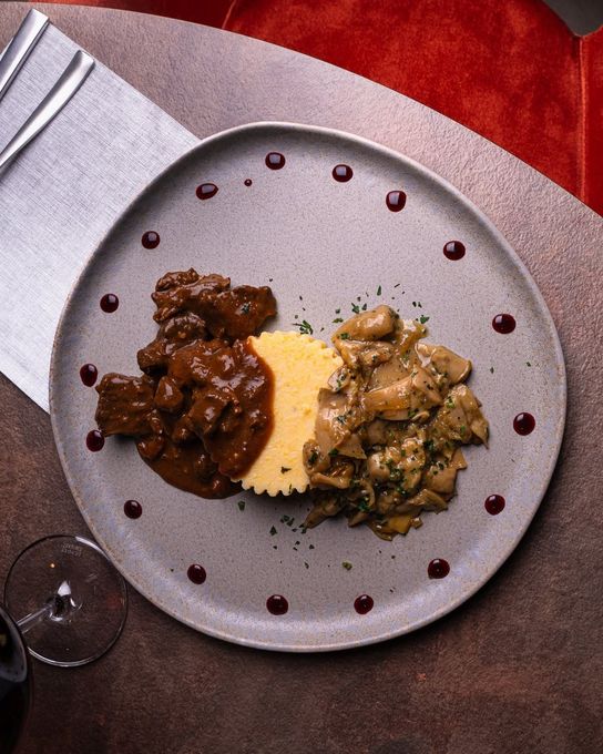 Un pasto gourmet servito al tavolo con due salse su un piatto bianco, su una tovaglia rossa.