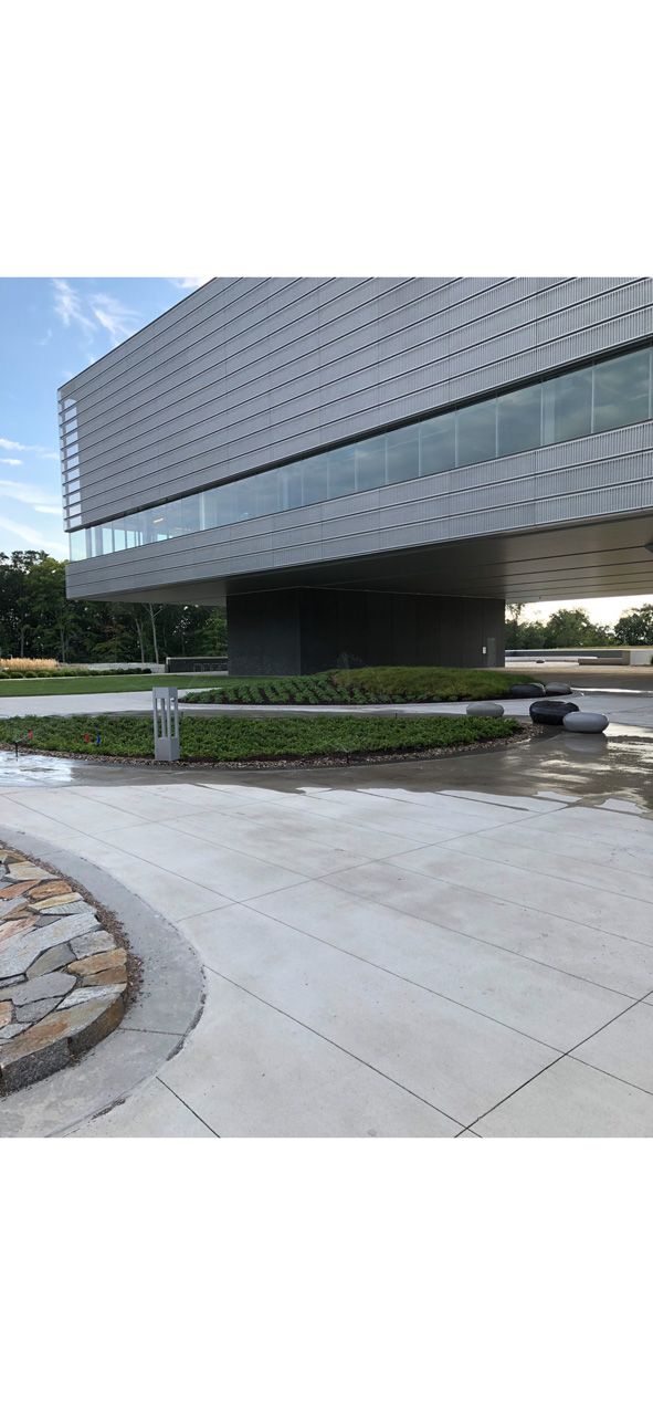 Modern glass office building with a cantilevered upper floor over a landscaped walkway