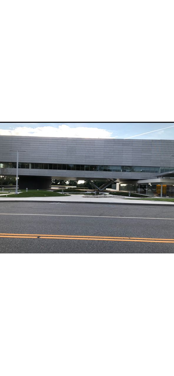 Modern gray building with horizontal windows and a parking lot in front