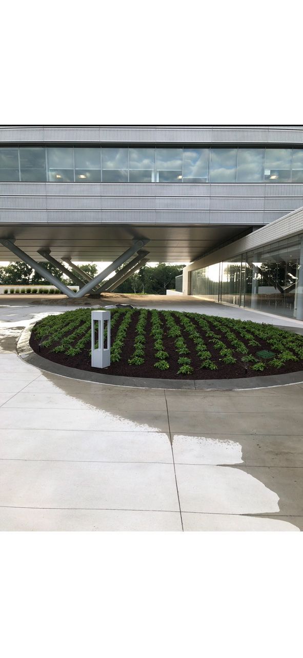 Modern building entrance with a circular flower bed and overhead walkway