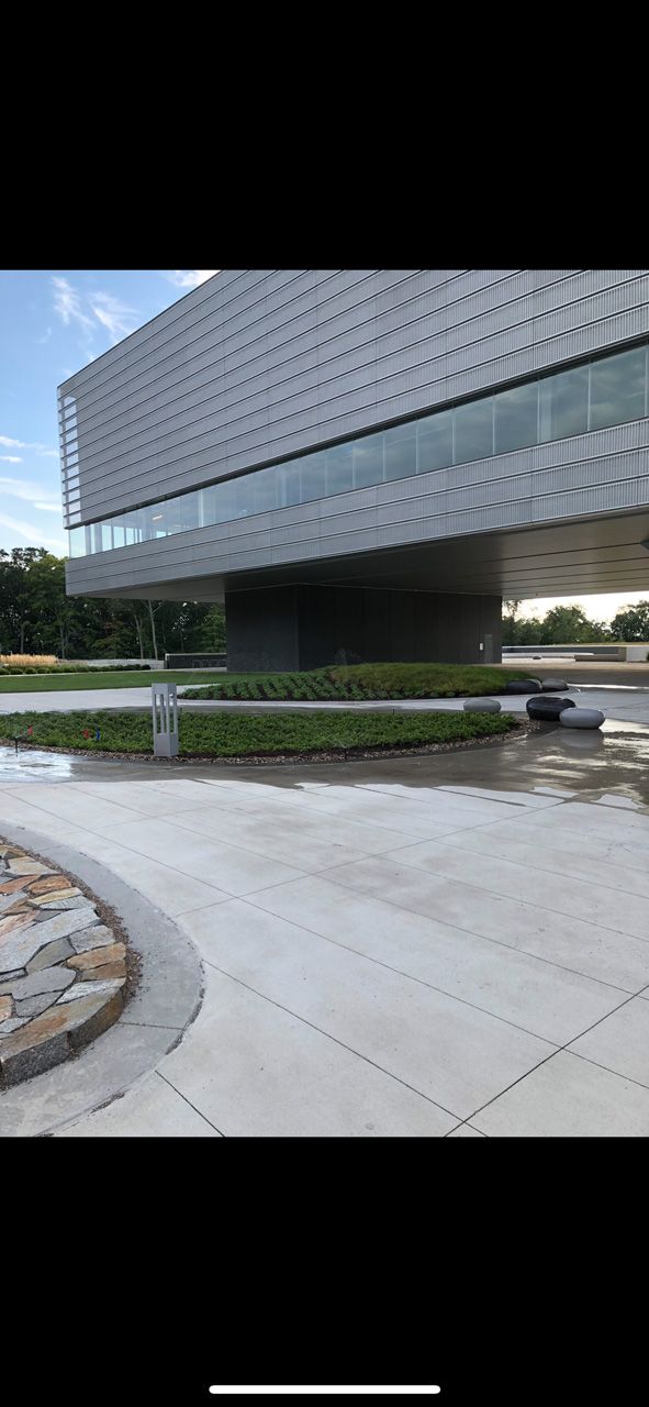 Modern glass-and-concrete building with landscaped walkway and open plaza outdoors