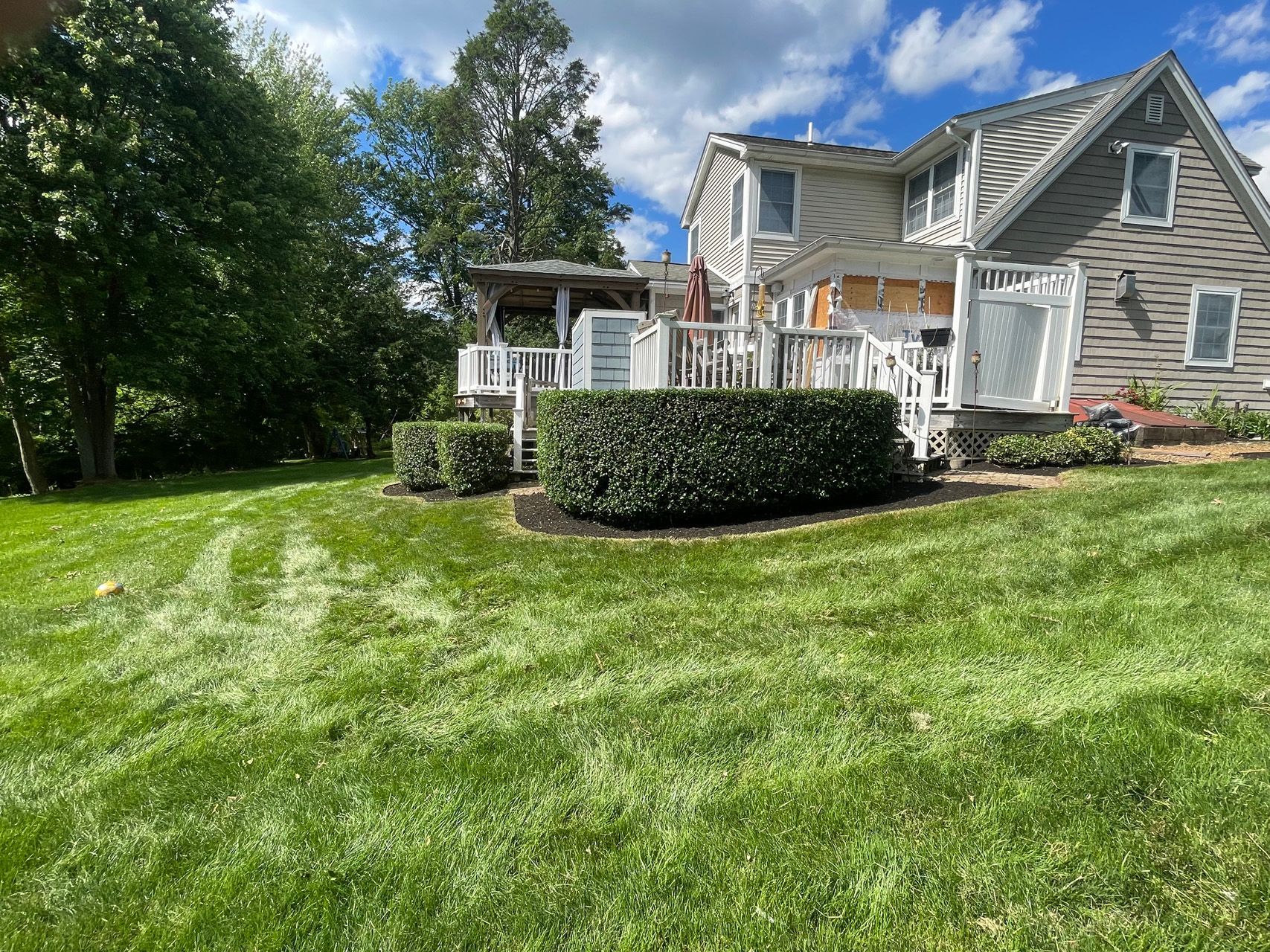 Suburban house with white porch and manicured lawn under a blue sky