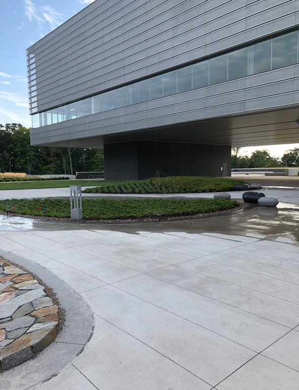 Modern glass office building with a cantilevered upper floor over a landscaped walkway