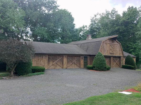 Rustic wooden lodge with a stone courtyard, surrounded by trees under an overcast sky