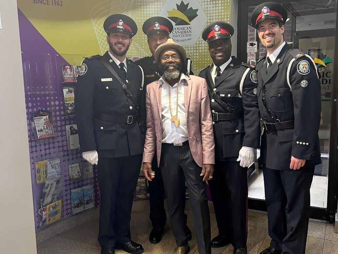 a group of police officers are posing for a picture with a man in a hat