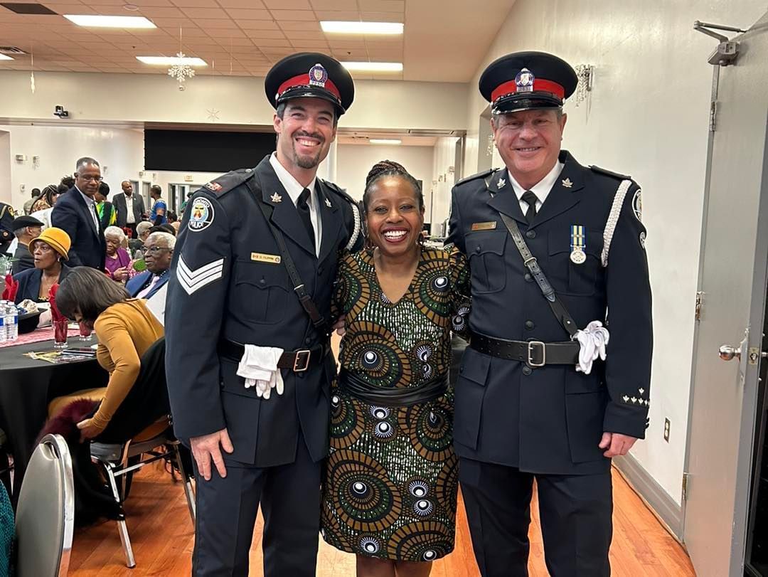 three police officers are posing for a picture with a woman in a dress