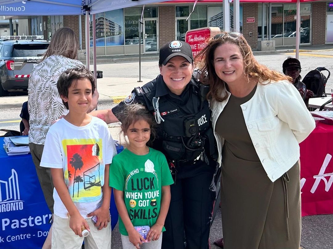 A group of people posing for a picture with a police officer and two children.